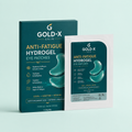 Gold-X Skin Anti-Fatigue Hydrogel Eye Patches shown with their dark teal retail box and a single white sachet on a pale mint background.